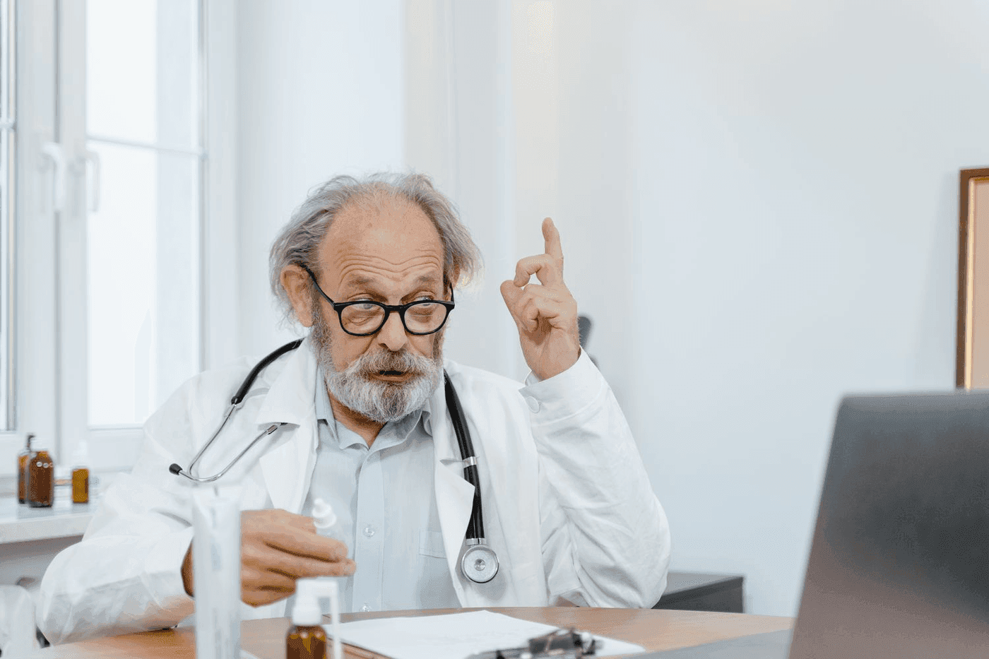 Medecin senior levant l index en signe d explication a son bureau