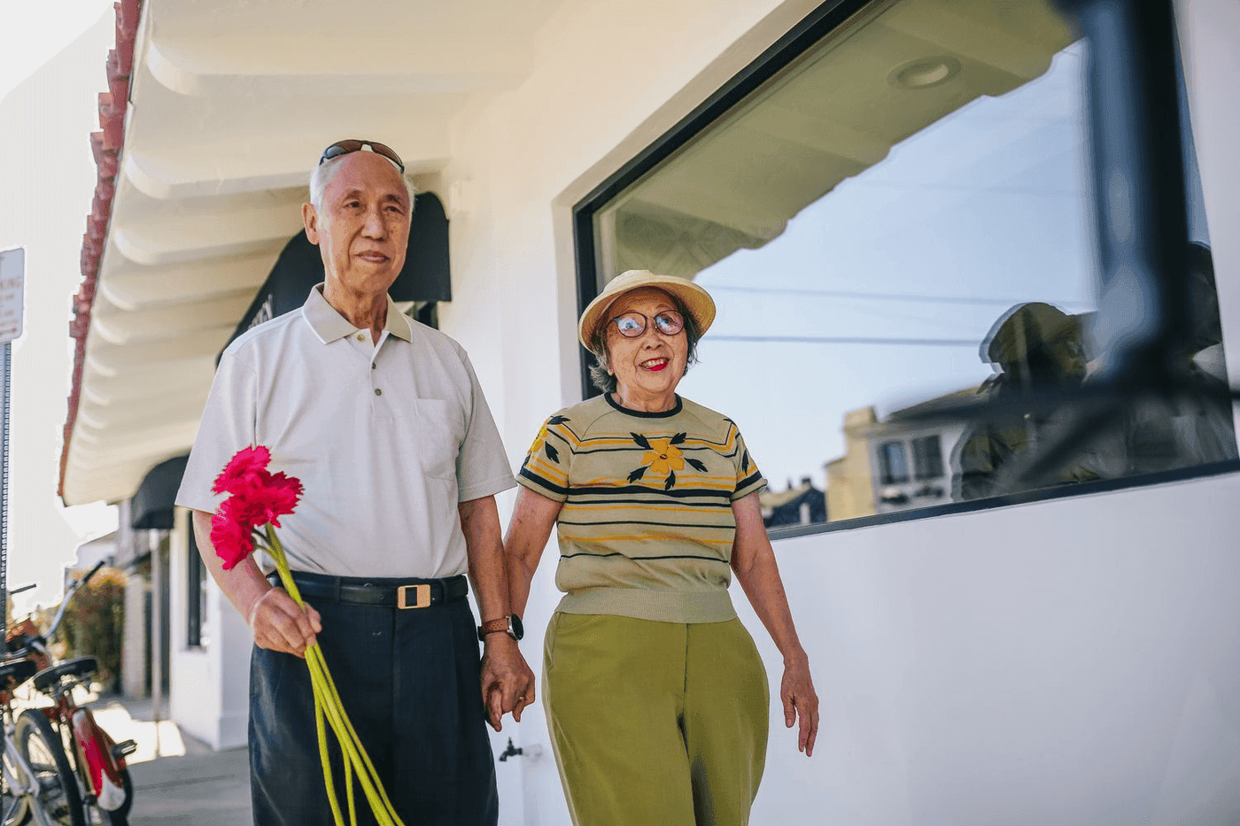 Couple de personnes agees marchant ensemble, un bouquet a la main