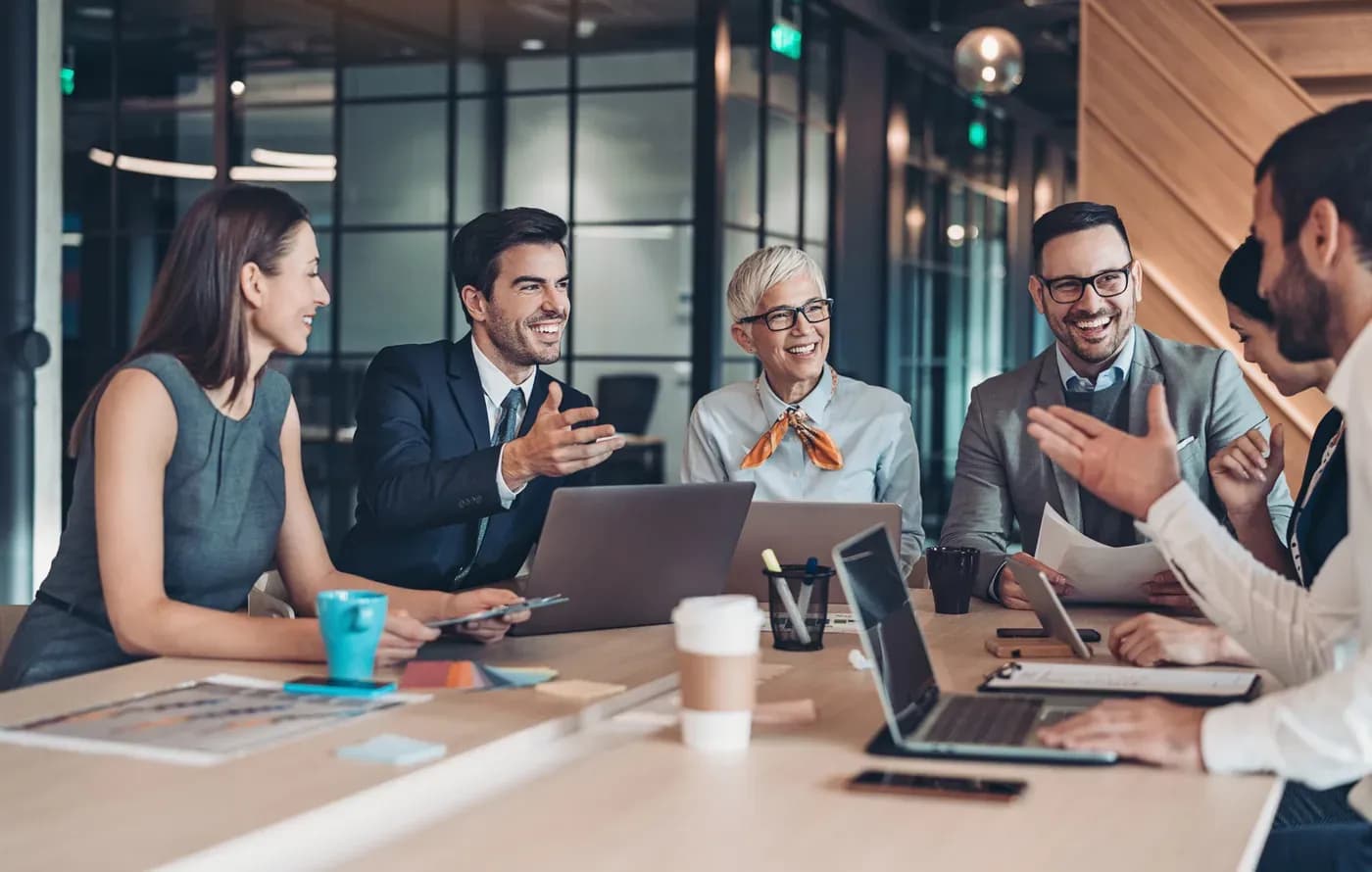 Équipe d'entreprise réunie autour d'une table de travail, souriante et collaborative