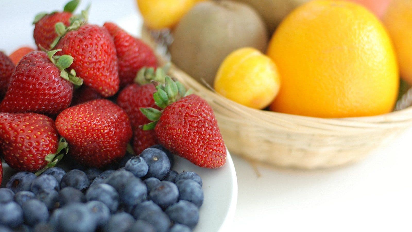 Corbeille de fraises, myrtilles et agrumes sur fond clair