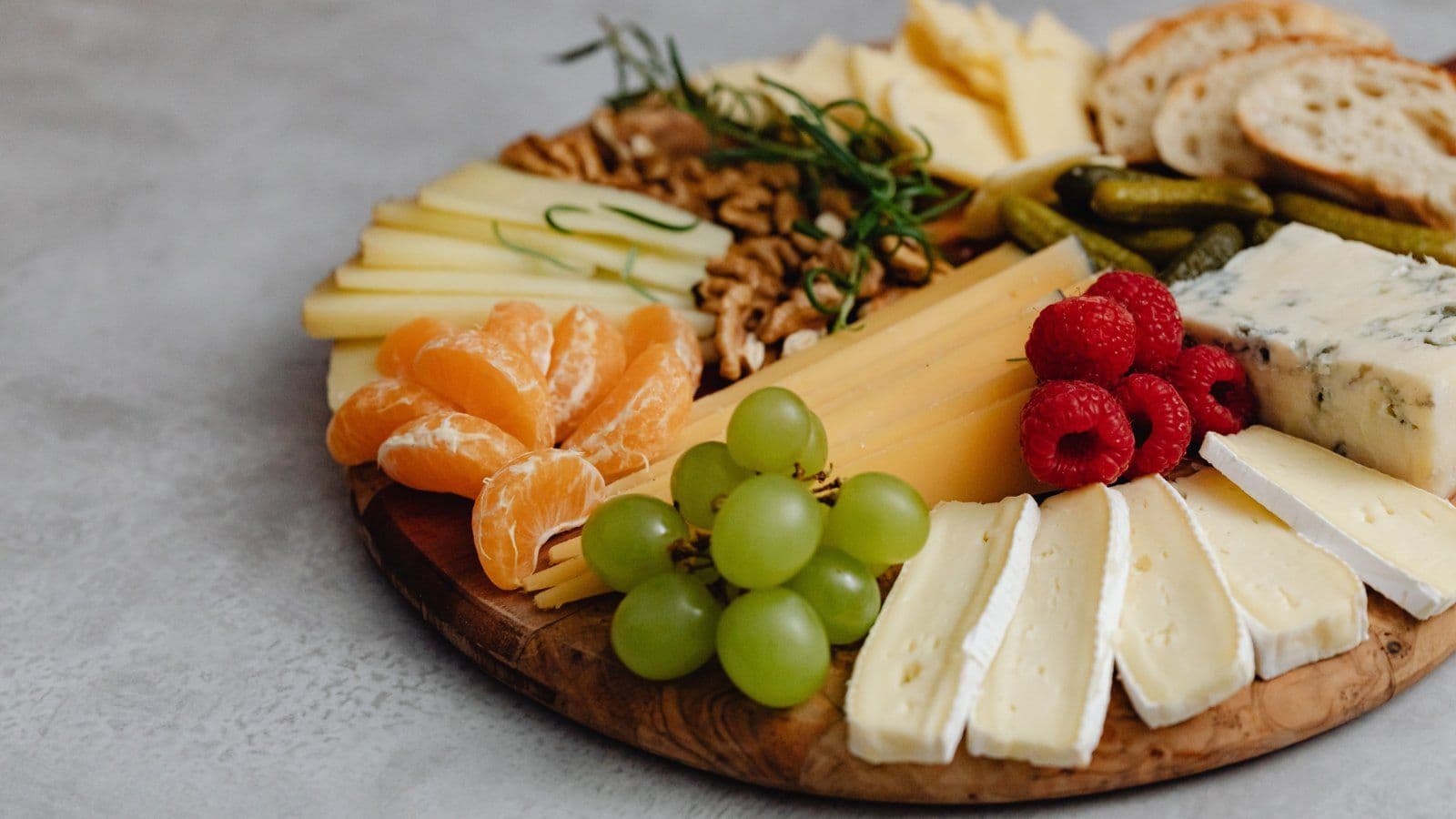Planche de fromages accompagnee de raisin, agrumes et fruits secs