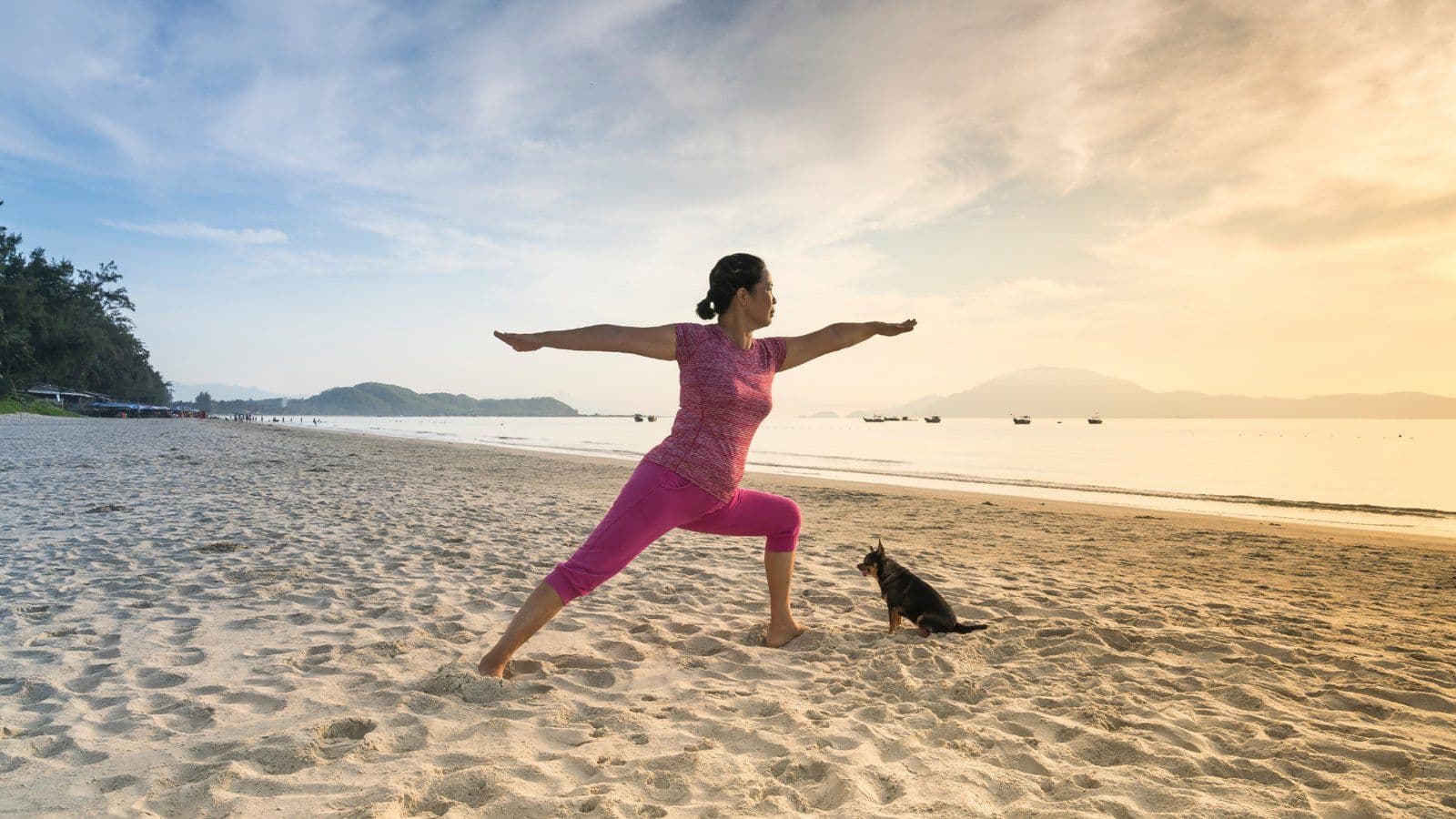 Femme en posture de yoga du guerrier sur une plage au lever du soleil