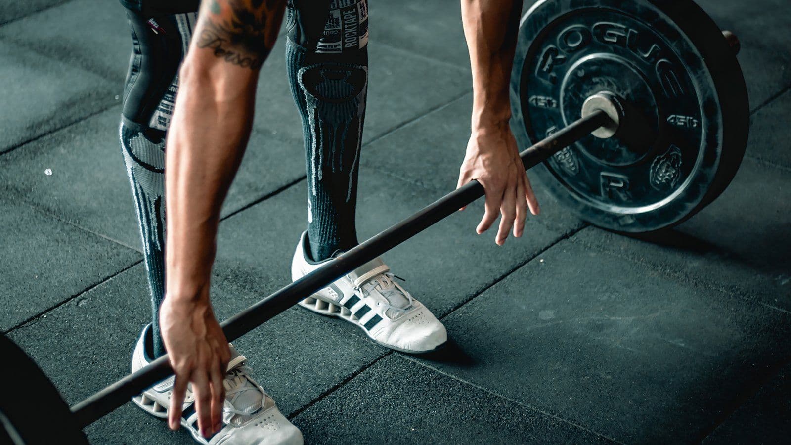 Mains d un athlete saisissant une barre de musculation chargee au sol