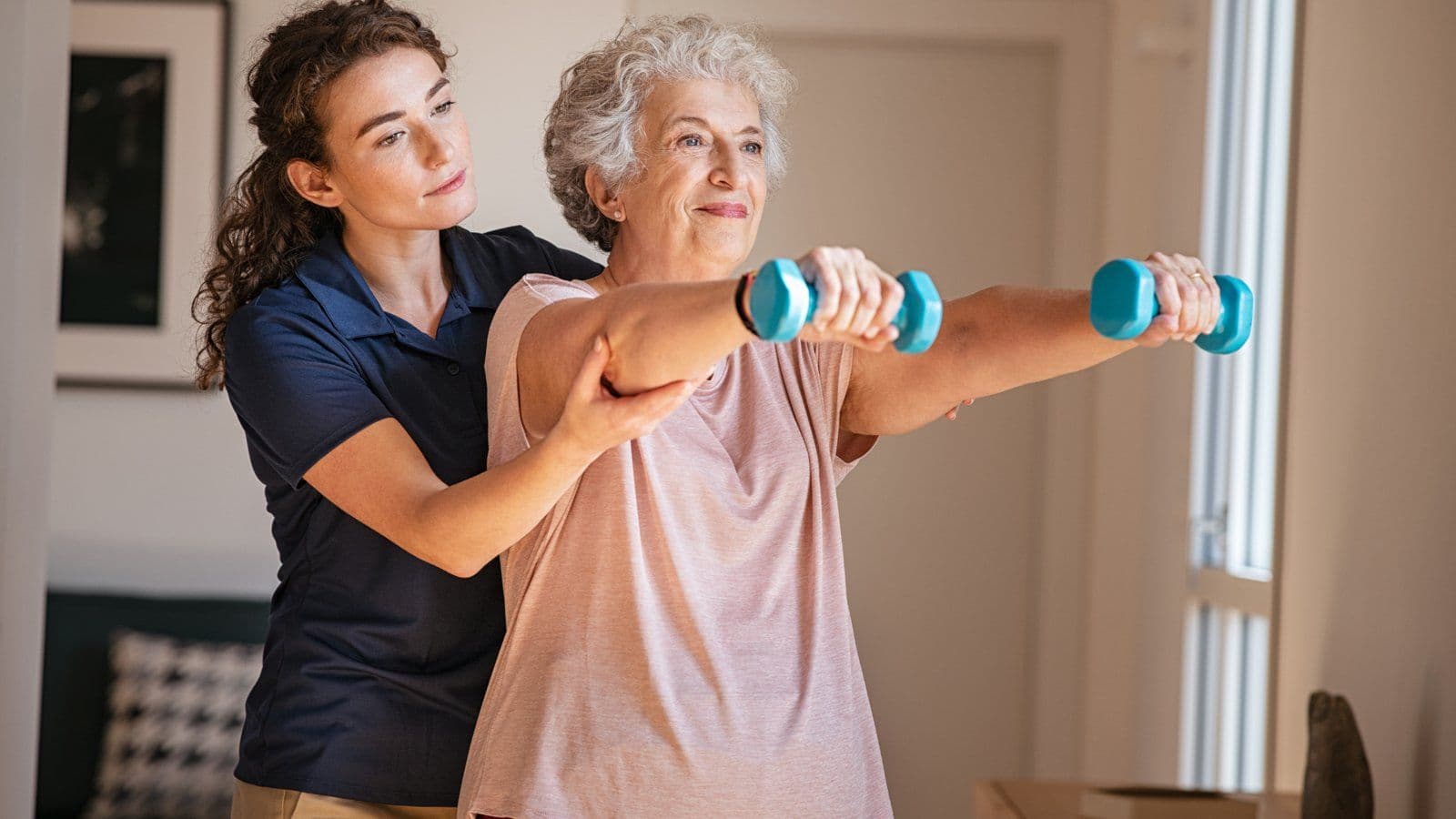 Coach guidant une femme senior dans un exercice avec halteres legers