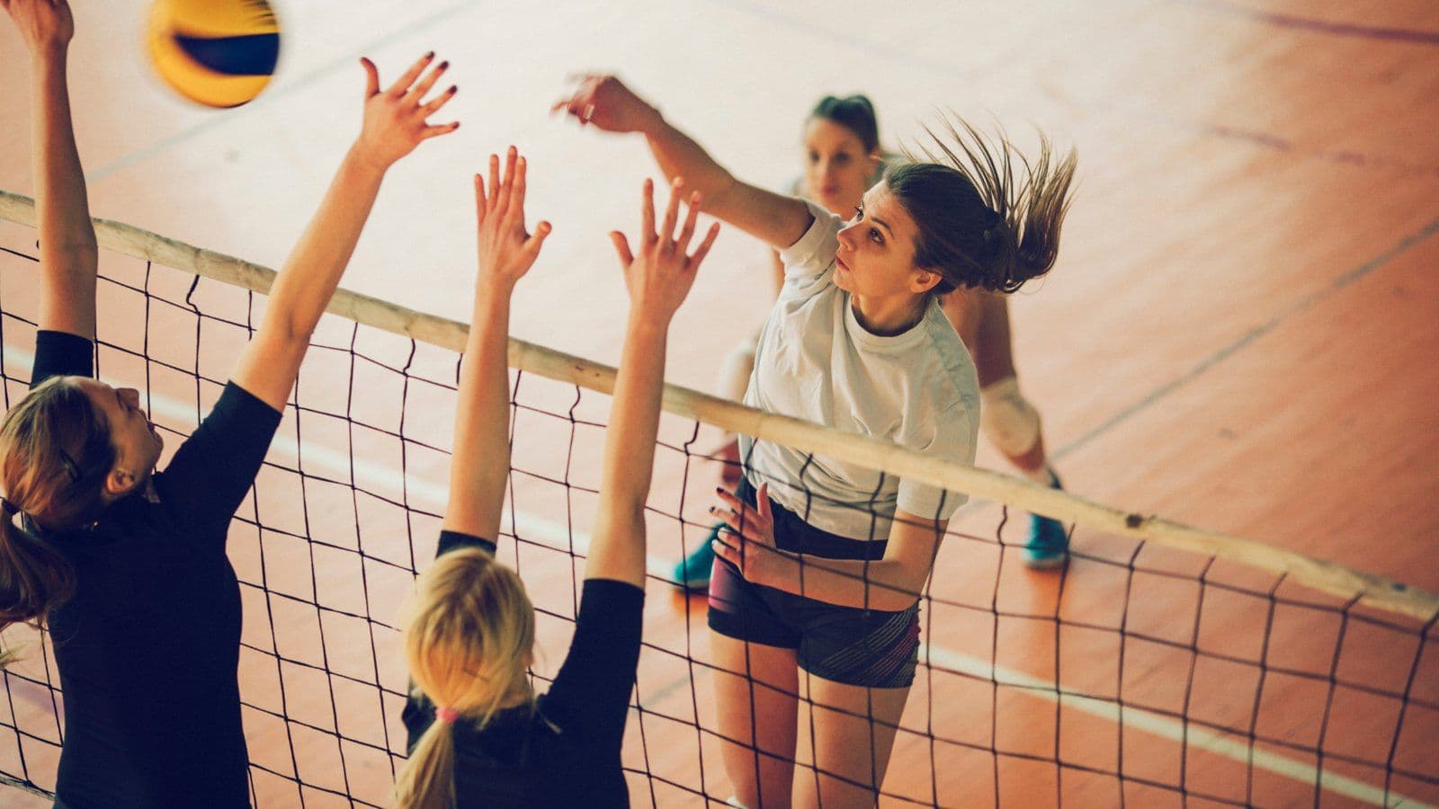 Joueuses de volley celebrant un point les bras leves au filet