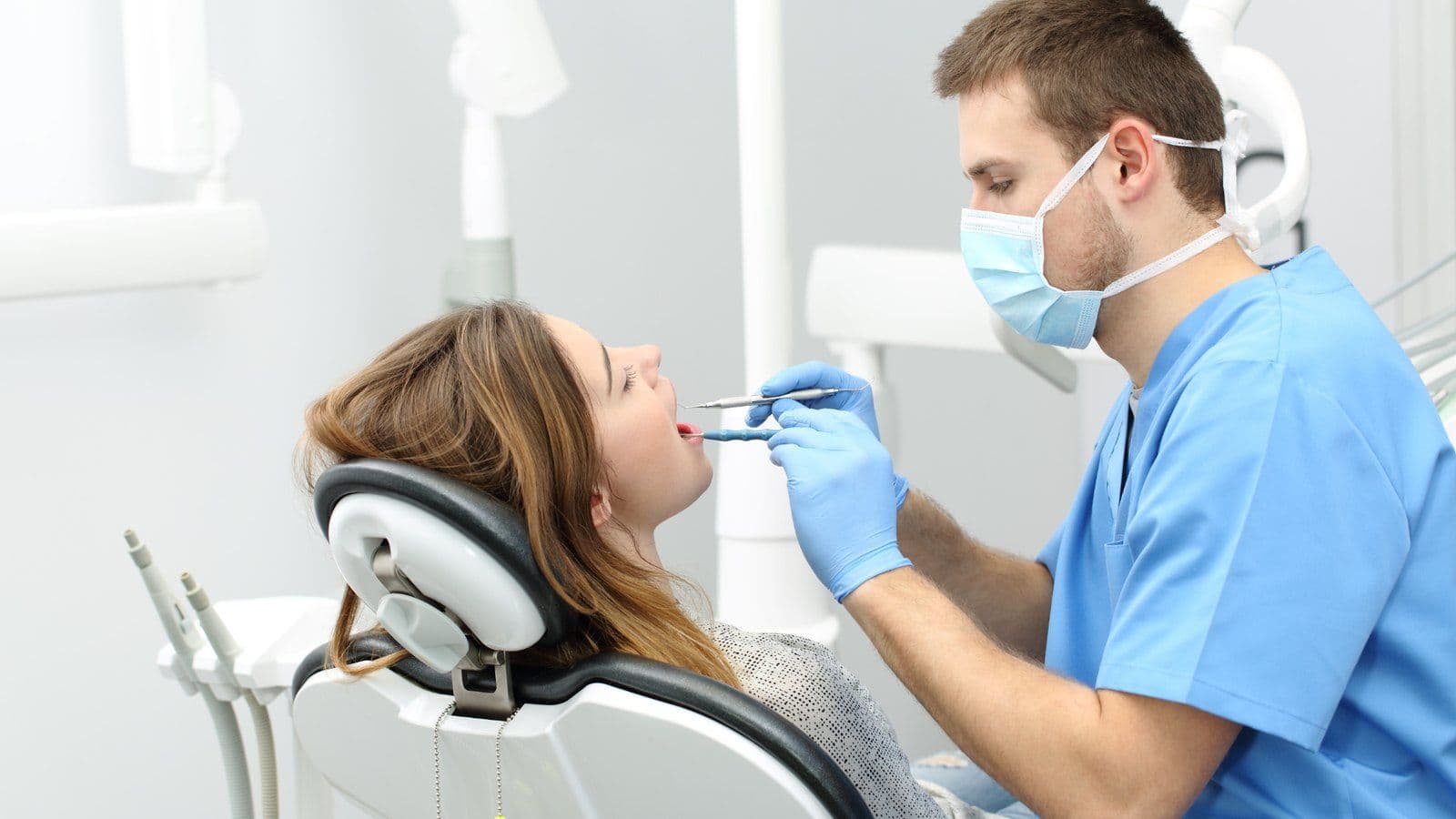 Dentiste examinant les dents d'une patiente installee au fauteuil