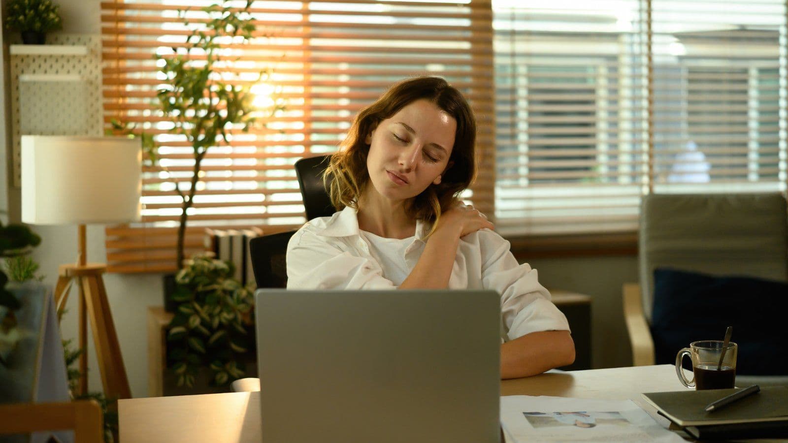 Femme se massant l epaule devant son ordinateur portable