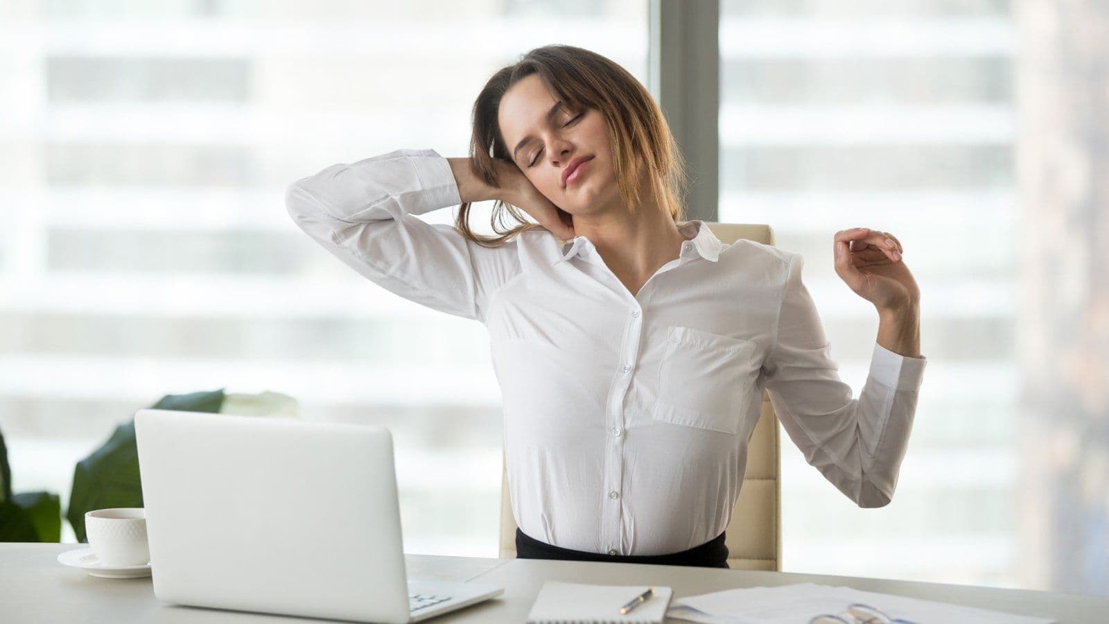 Femme s etirant les bras derriere le dos a son bureau