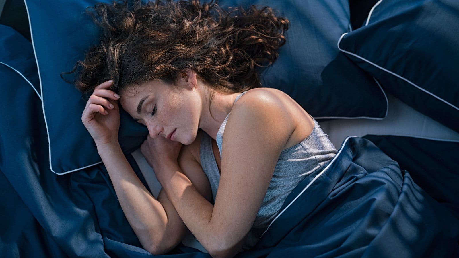 Femme dormant enroulee dans une parure de lit bleu nuit