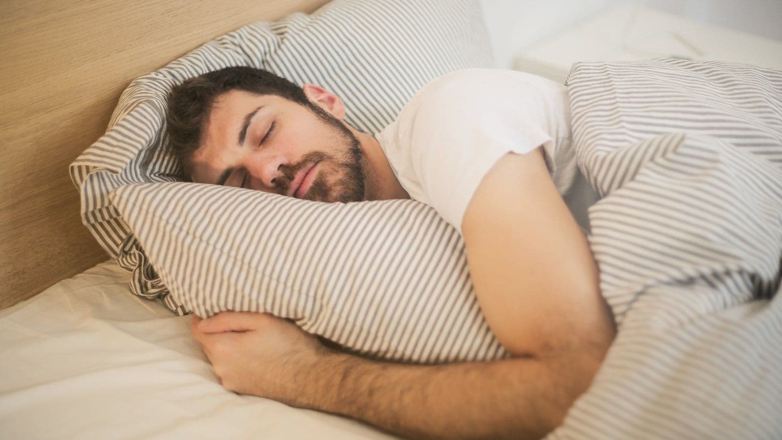 Homme dormant paisiblement, la tete enfoncee dans son oreiller
