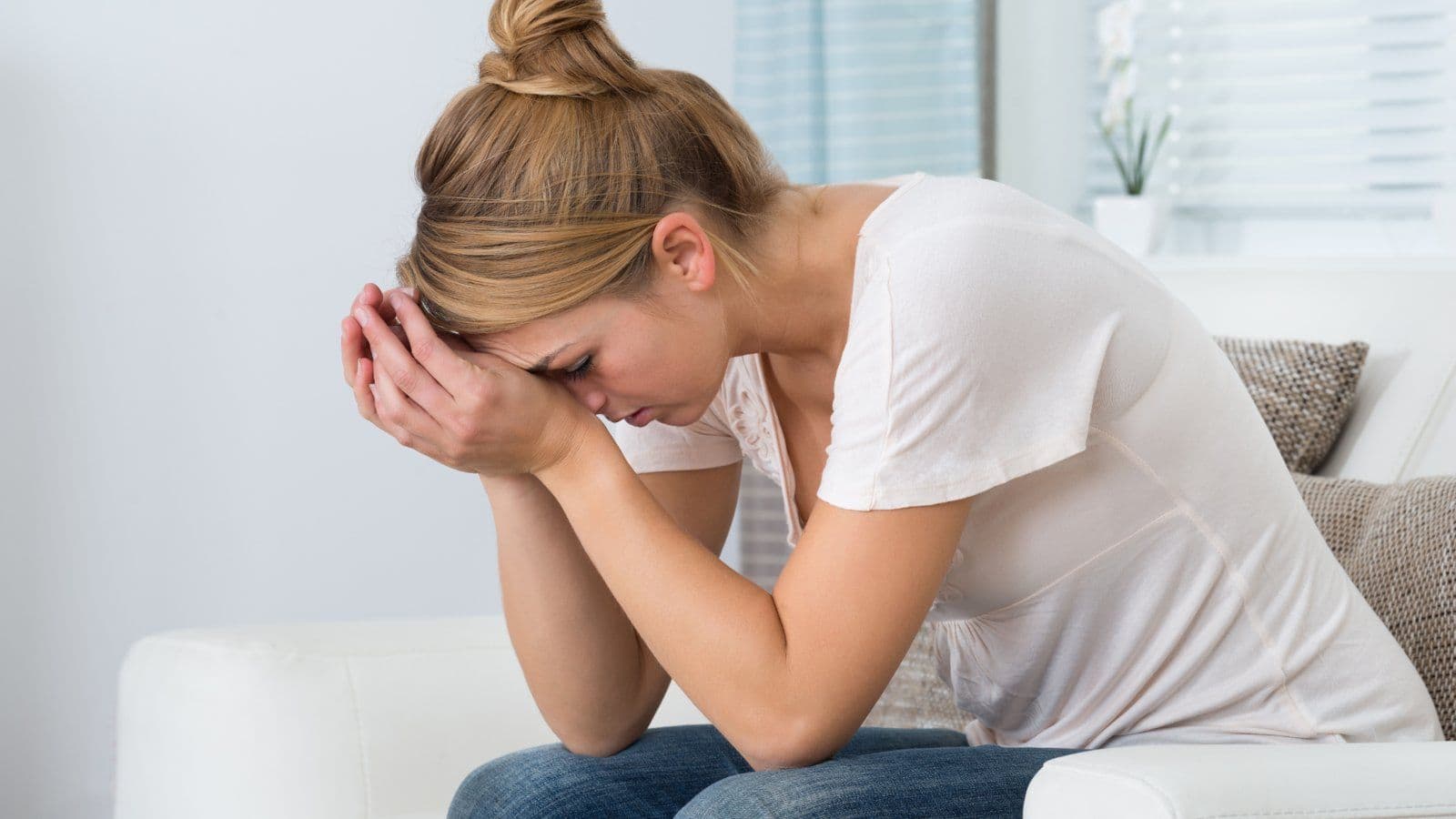 Femme assise sur un lit, la tete dans les mains