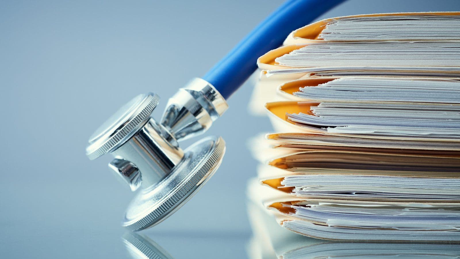 Stethoscope pose devant une pile de dossiers medicaux
