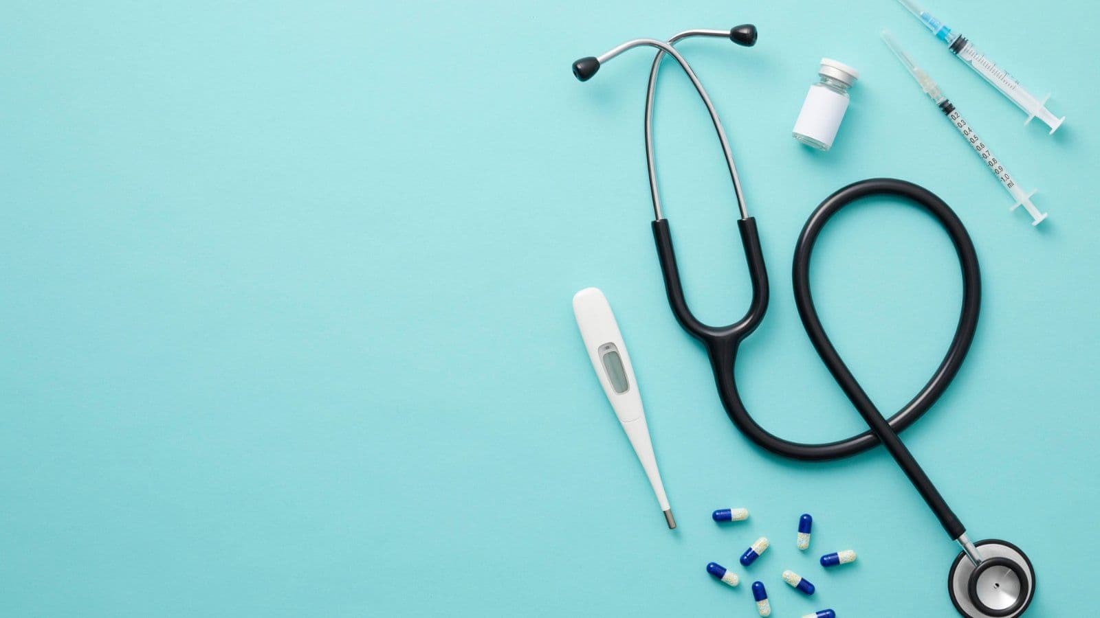 Stethoscope, thermometre, flacon et seringues sur fond turquoise