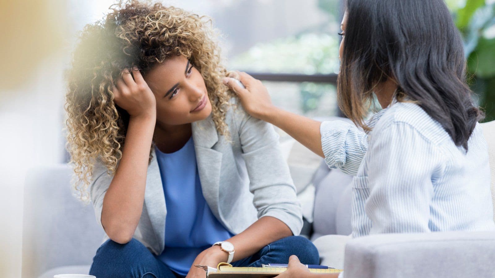 Femme reconfortee par une main posee sur son epaule lors d un entretien
