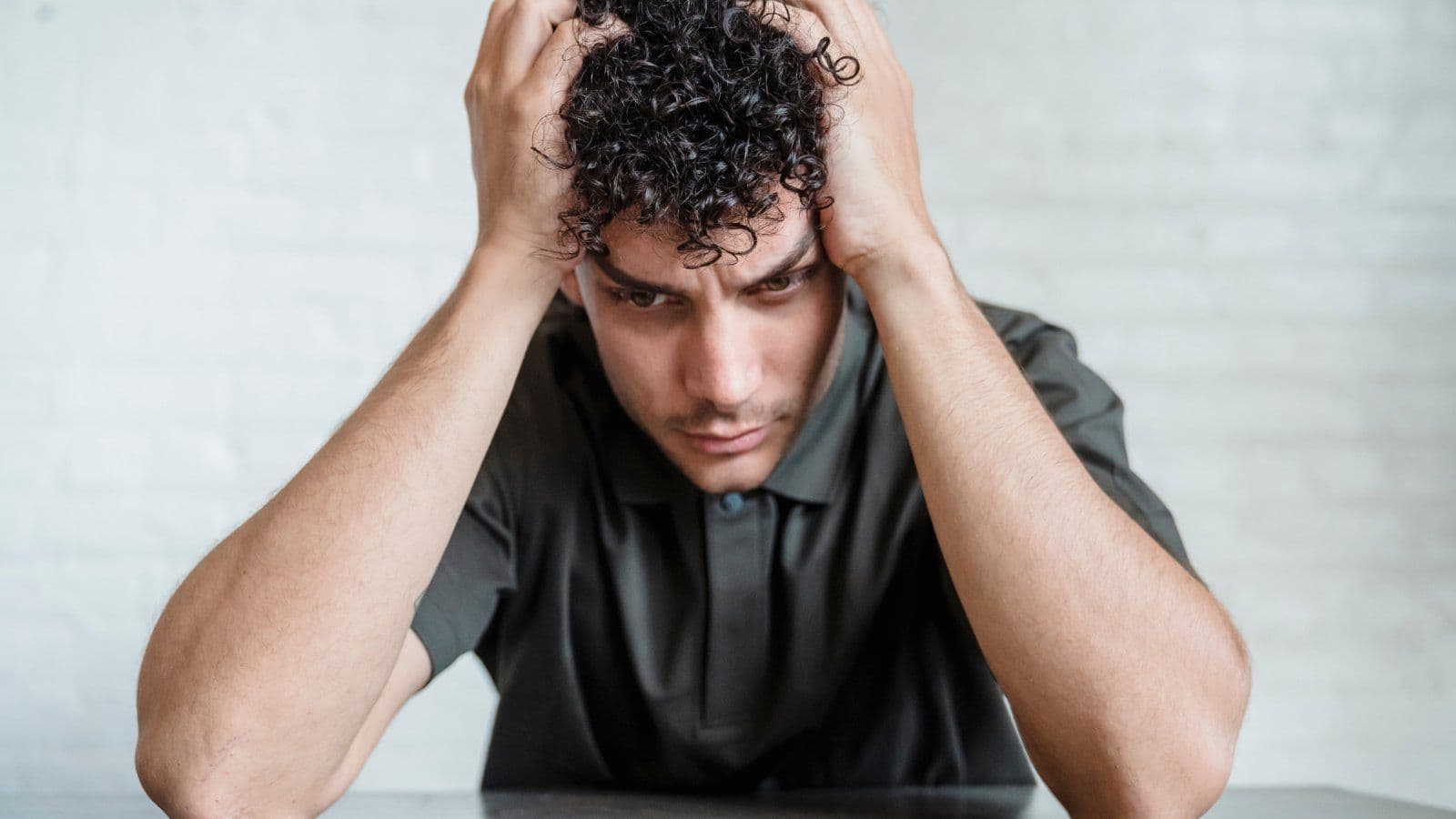 Homme assis a un bureau, les mains dans les cheveux, visiblement tendu