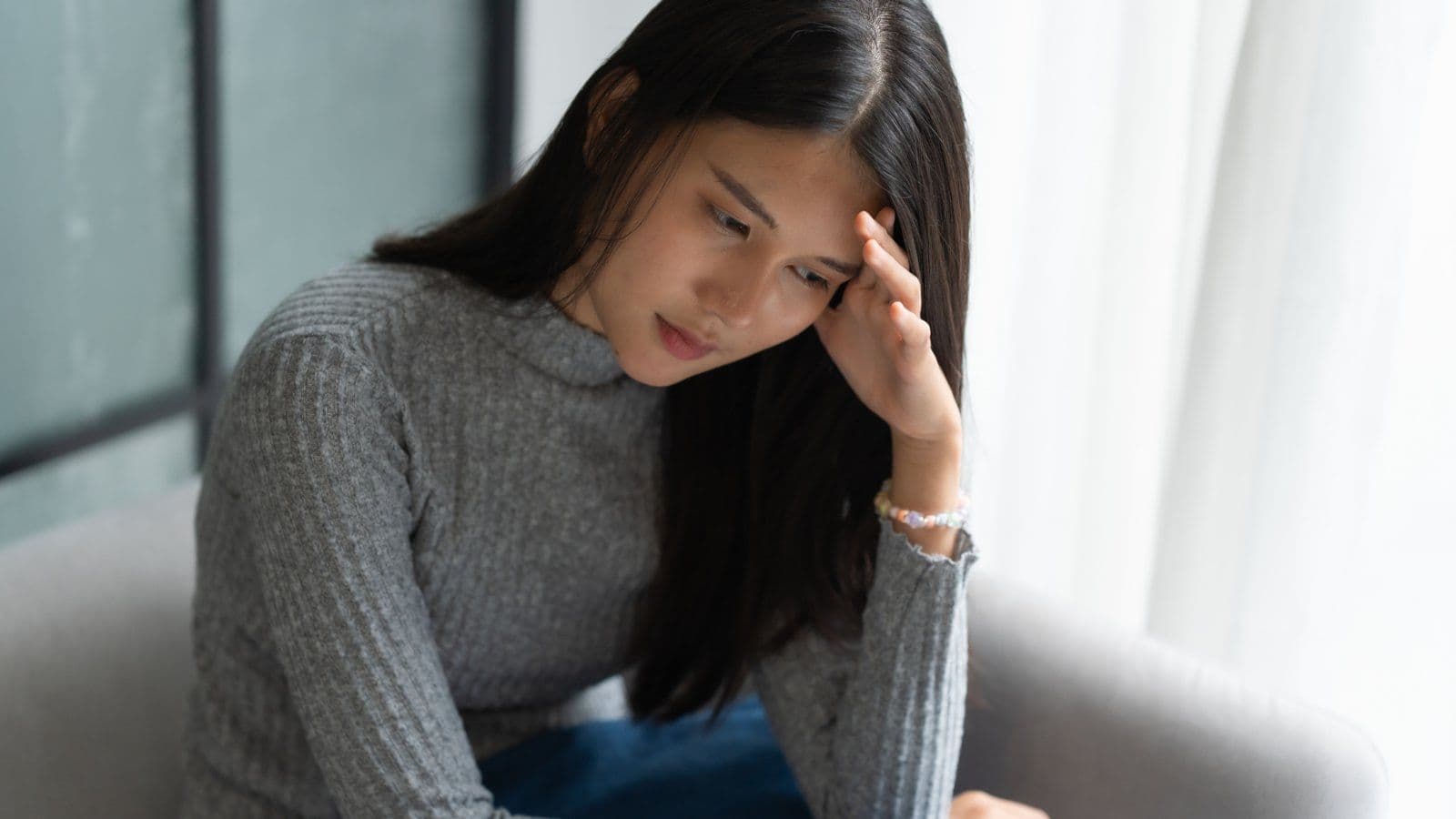 Jeune femme assise, la tete appuyee sur la main, l air preoccupe