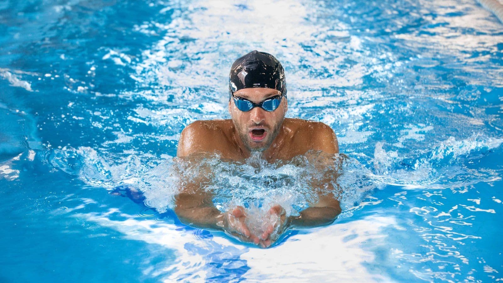 Nageur en brasse remontant respirer dans un bassin de piscine