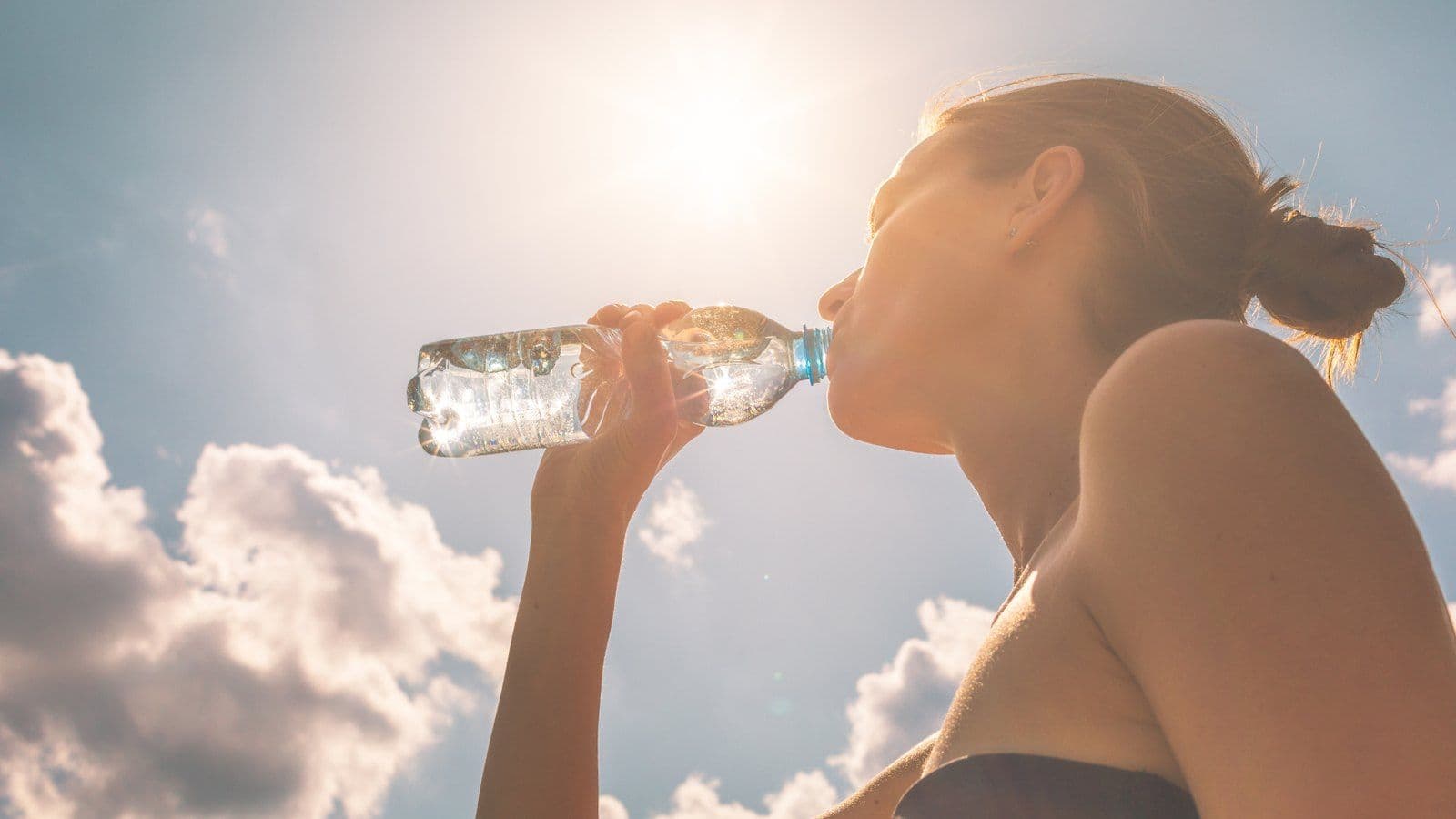 Femme buvant a la bouteille en plein soleil d'ete