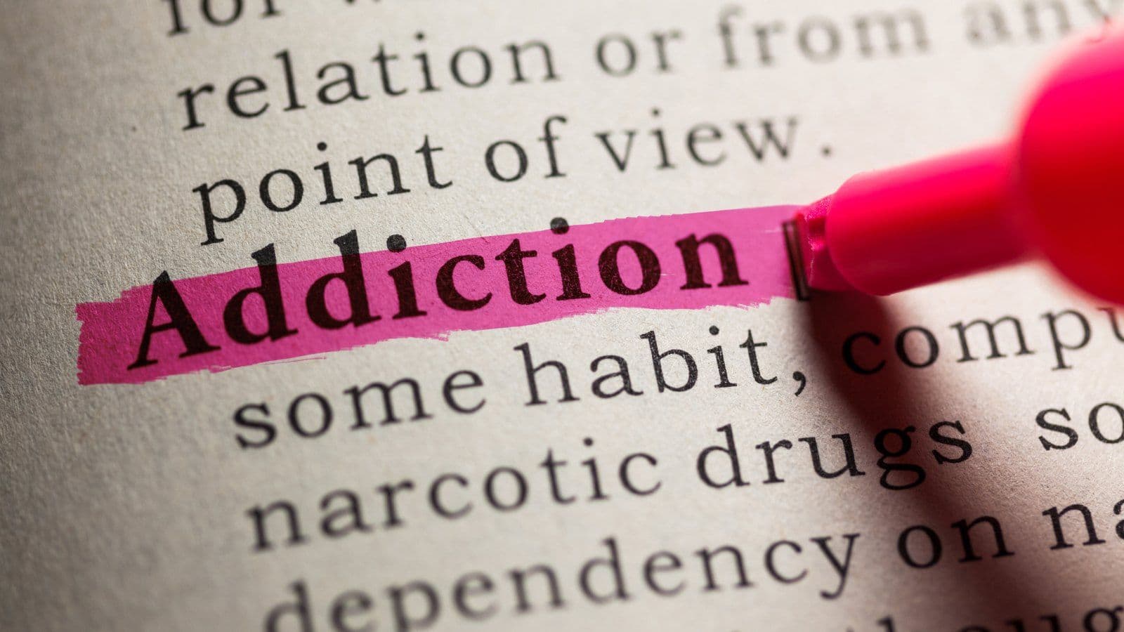 Le mot addiction surligne en rose dans la page d'un dictionnaire