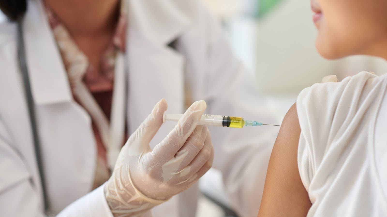 Medecin approchant une seringue du bras d'une patiente