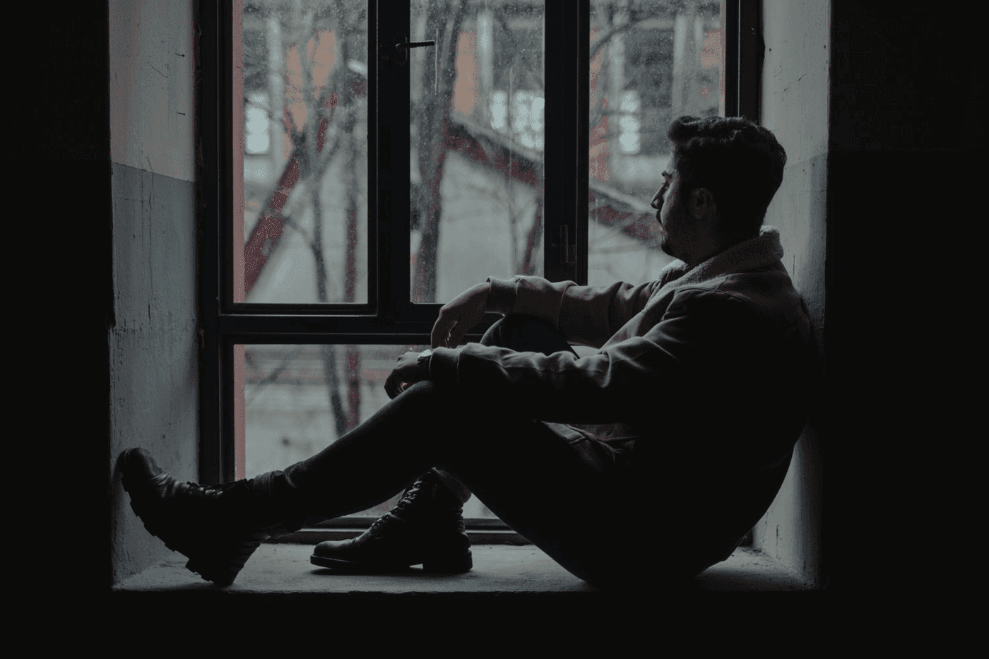 Silhouette d un homme assis a une fenetre dans une piece sombre