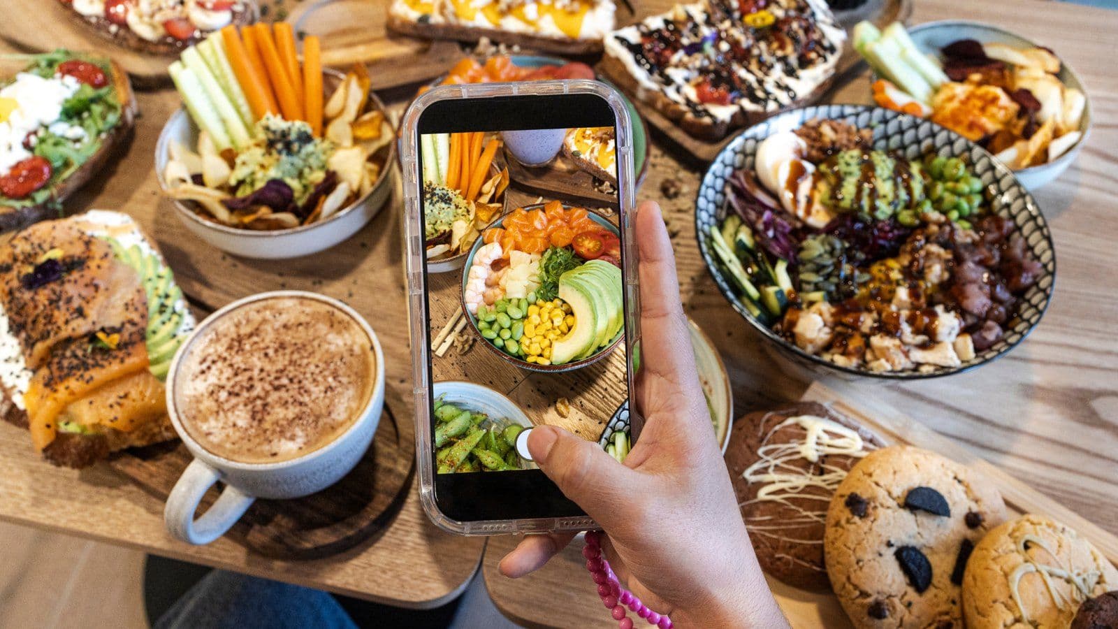 Main photographiant au smartphone une table de plats varies