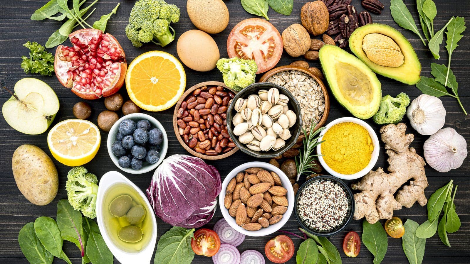 Fruits, noix, graines et epices disposes en petits bols sur ardoise