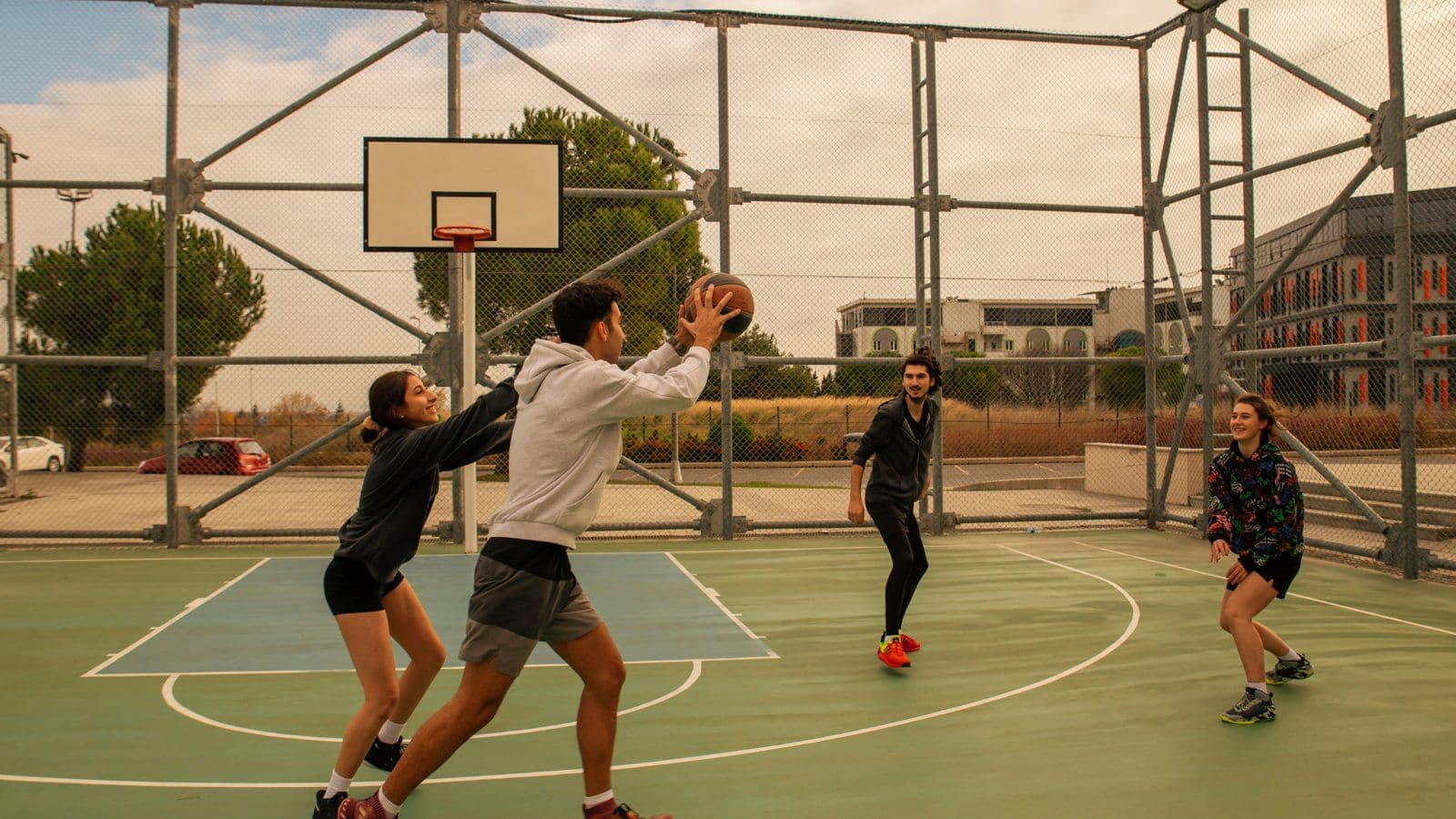 Groupe d amis jouant au basket sur un terrain grillage