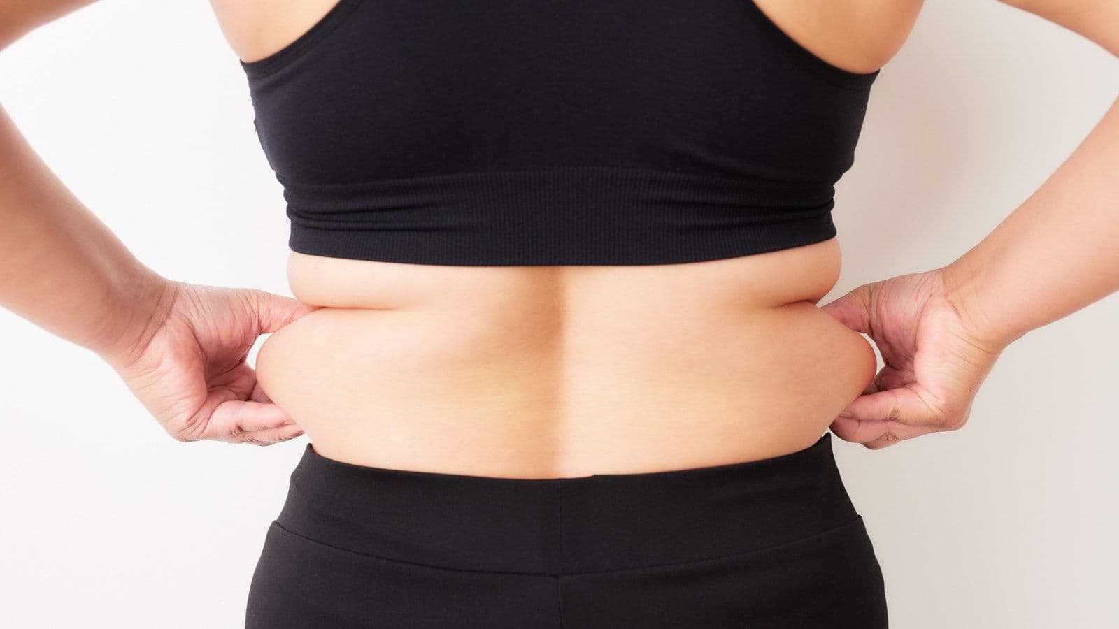 Vue de dos d'une personne pincant un pli de graisse abdominale