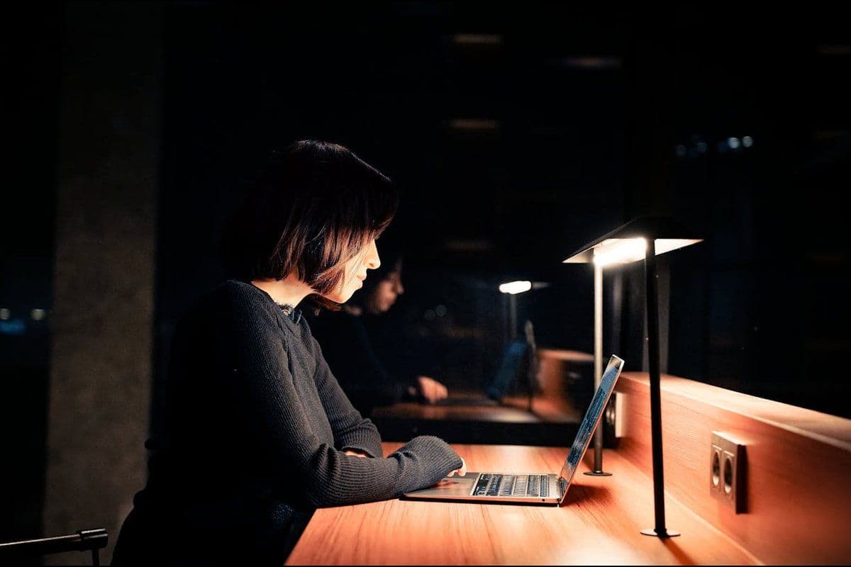 Personne seule travaillant tard le soir, éclairée par une lampe de bureau