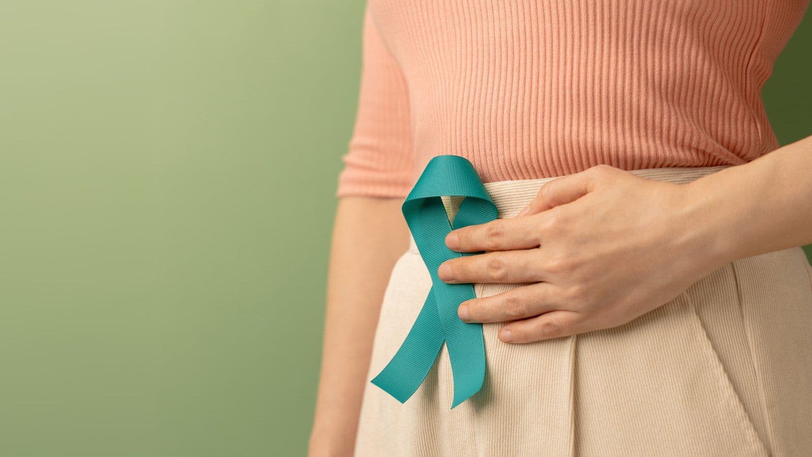 Femme portant un ruban turquoise, symbole du depistage du cancer gynecologique