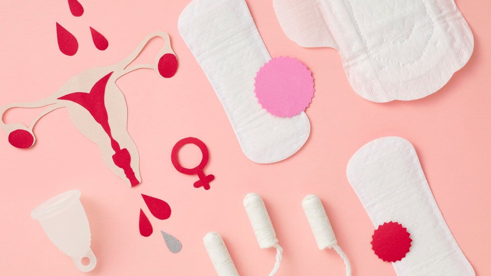 Protections hygieniques et symbole feminin disposes sur fond rose
