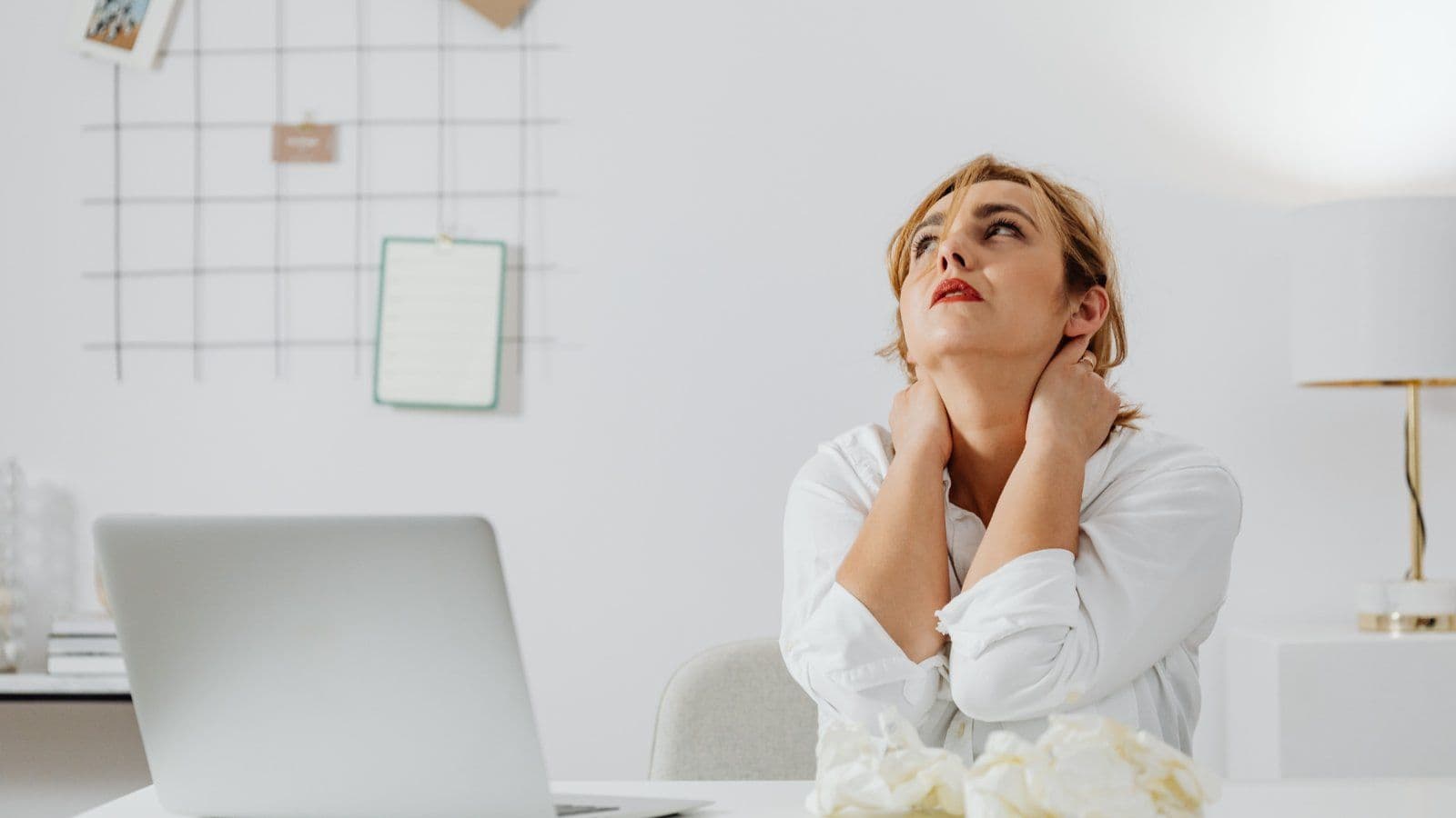 Femme au bureau etirant sa nuque, papiers froisses devant elle