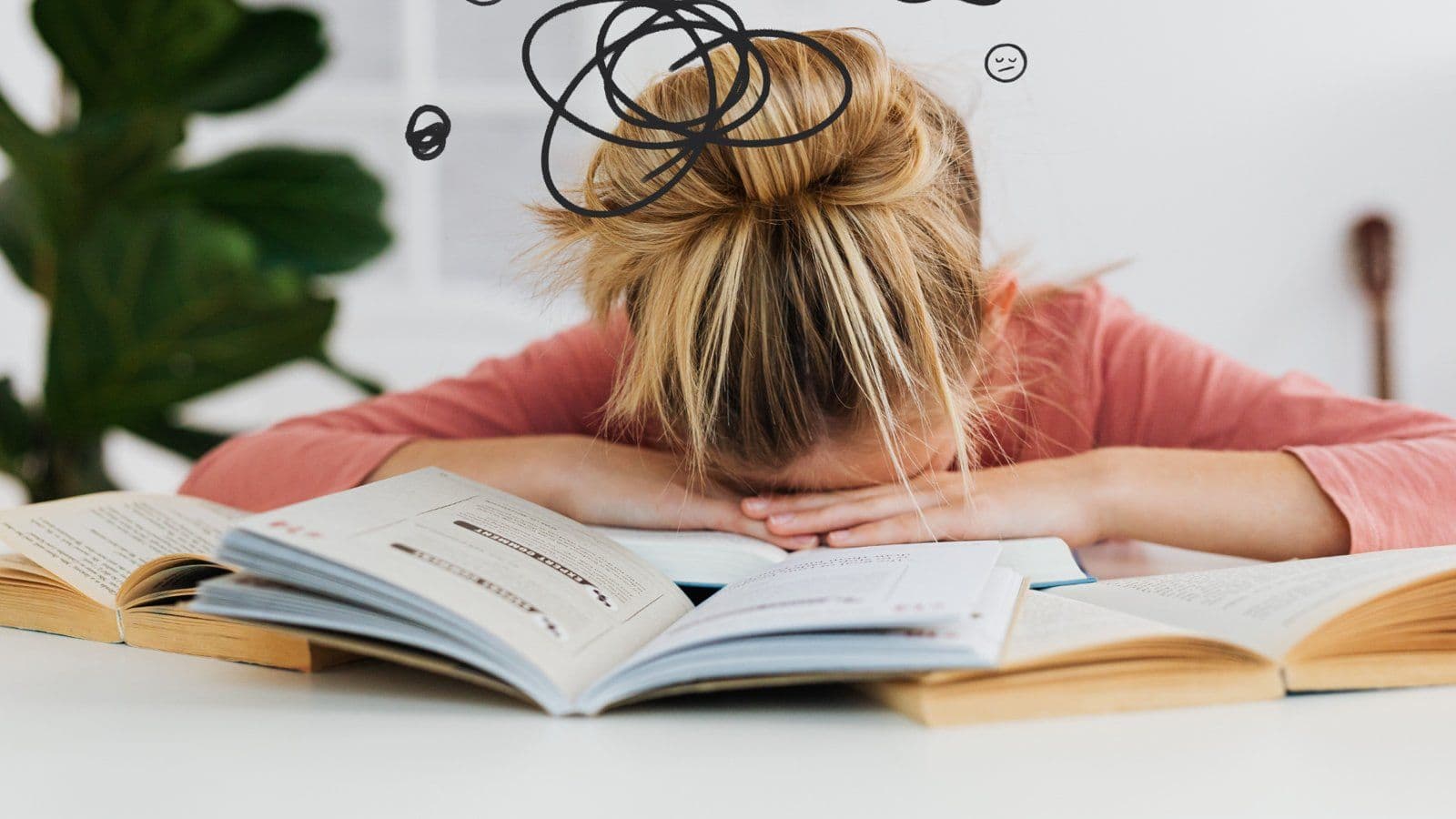Etudiante endormie sur ses livres ouverts, gribouillage au-dessus de la tete