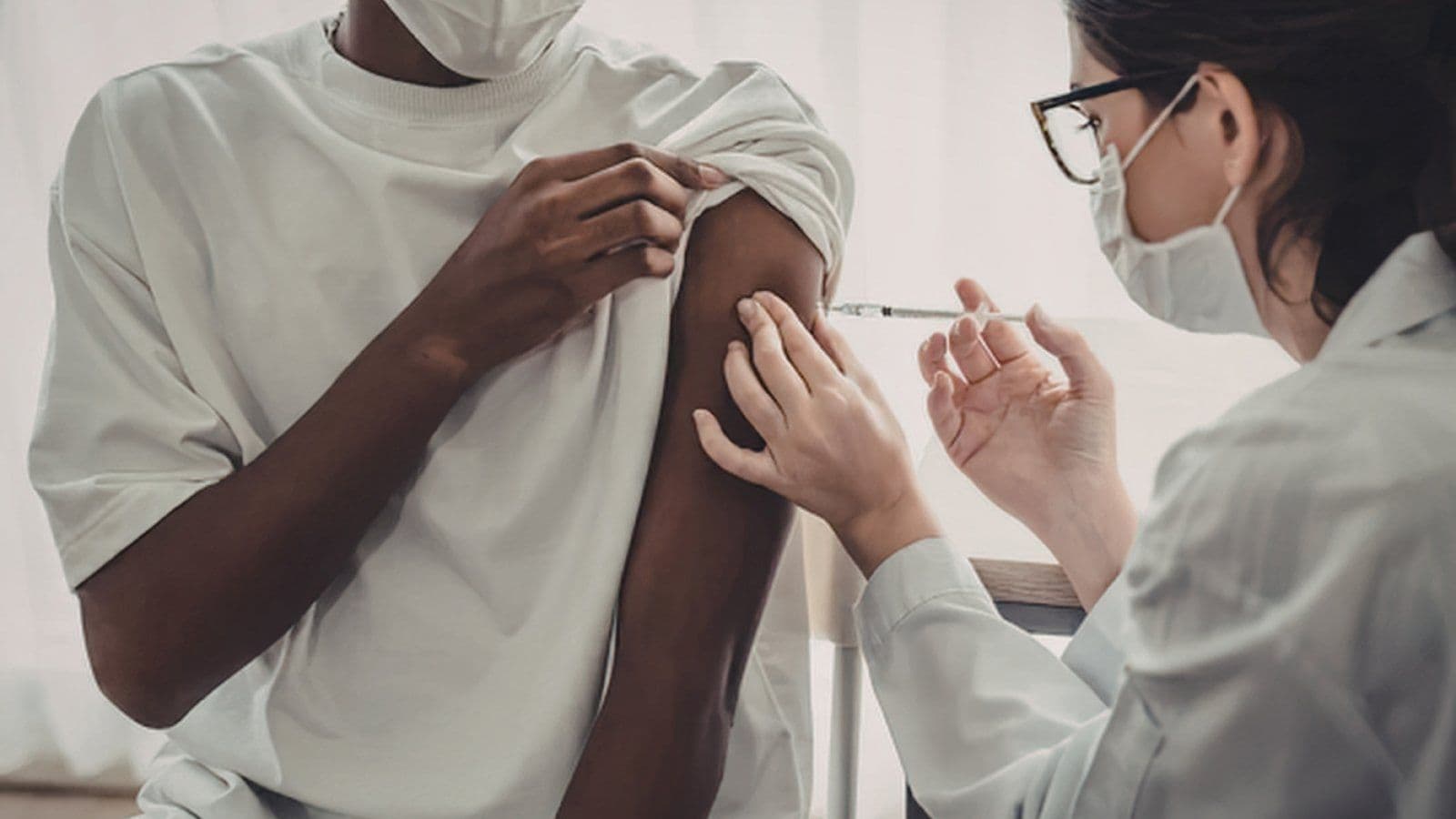 Soignante vaccinant un homme dans le bras en cabinet