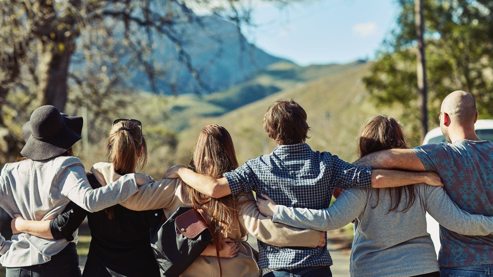 Groupe d amis enlaces de dos face a un paysage de montagne