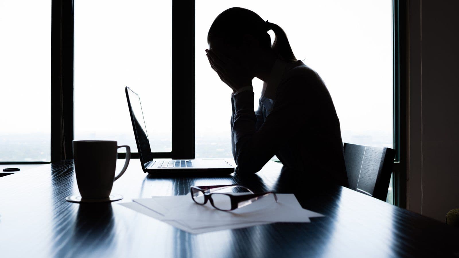 Silhouette d une personne accablee devant son ordinateur a contre-jour