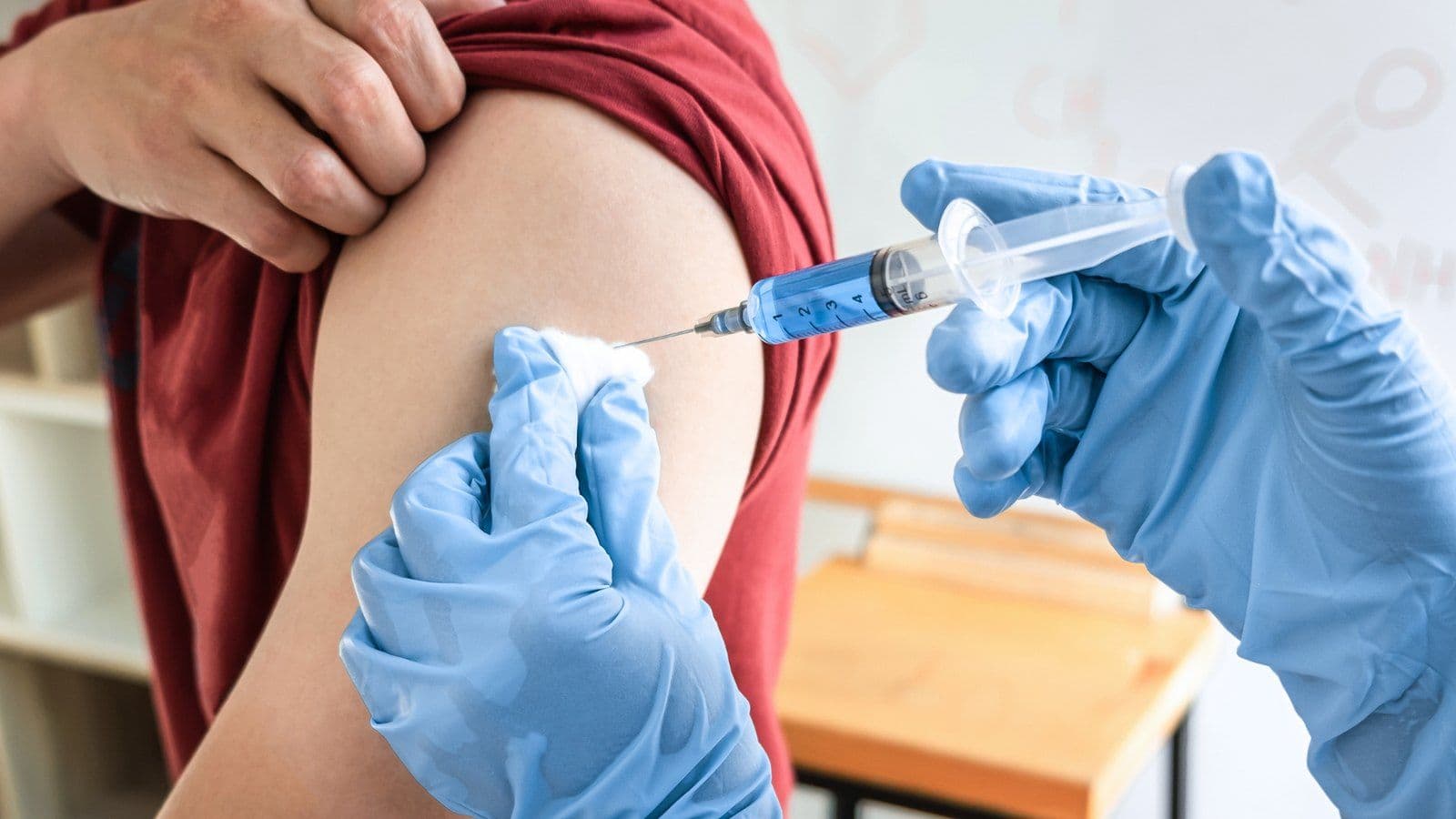 Injection d'un vaccin dans le bras d'un patient par un soignant gante