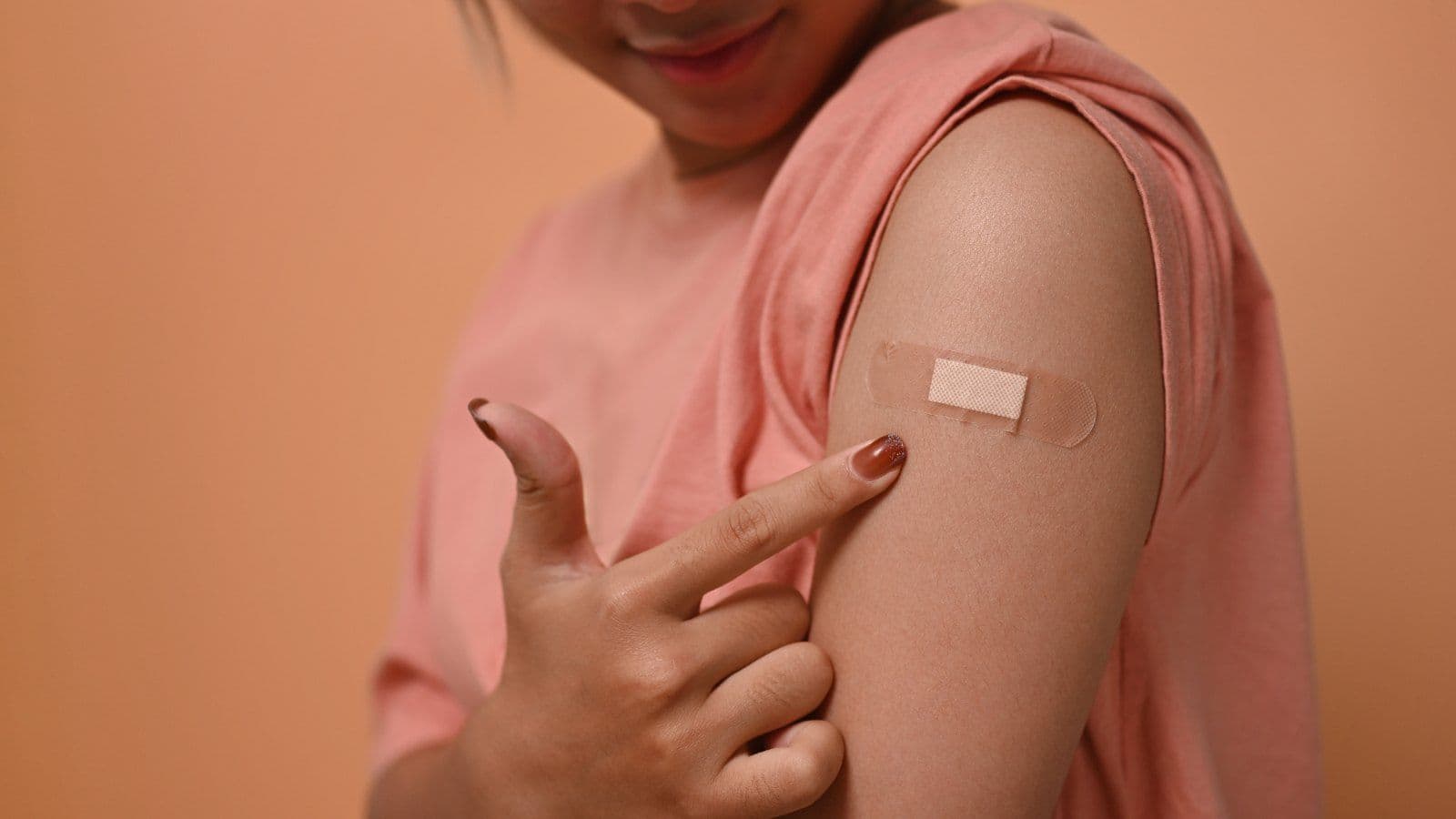 Personne montrant du doigt le pansement laisse par sa vaccination
