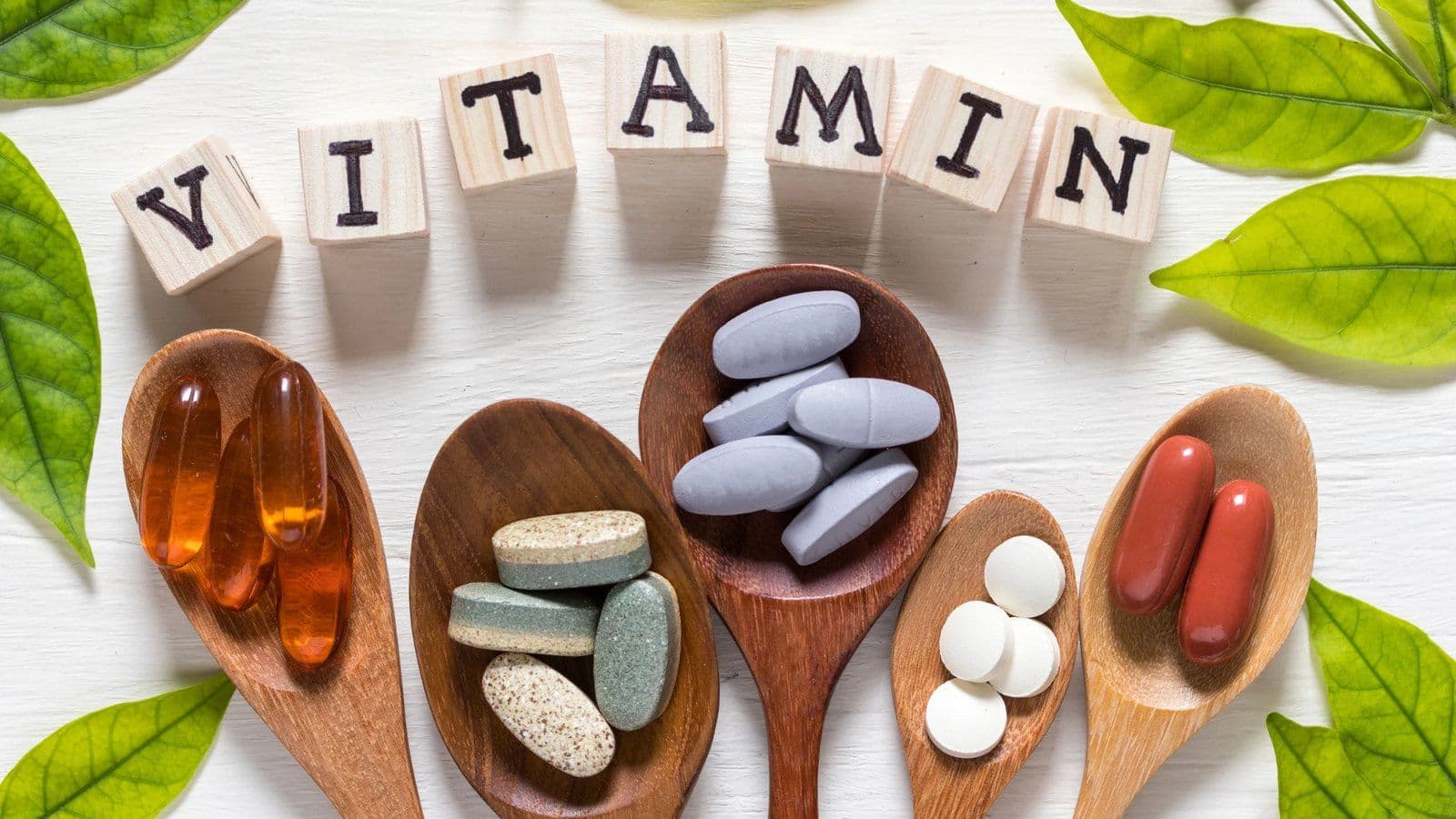 Cuilleres en bois remplies de comprimes et gelules sous le mot Vitamin